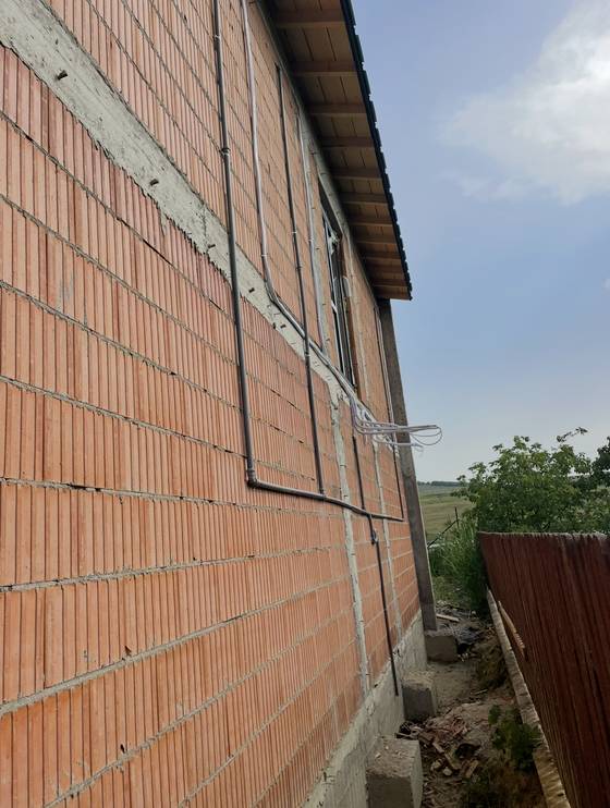 Casă · trasee prinse pe fațadă, înainte de termoizolație